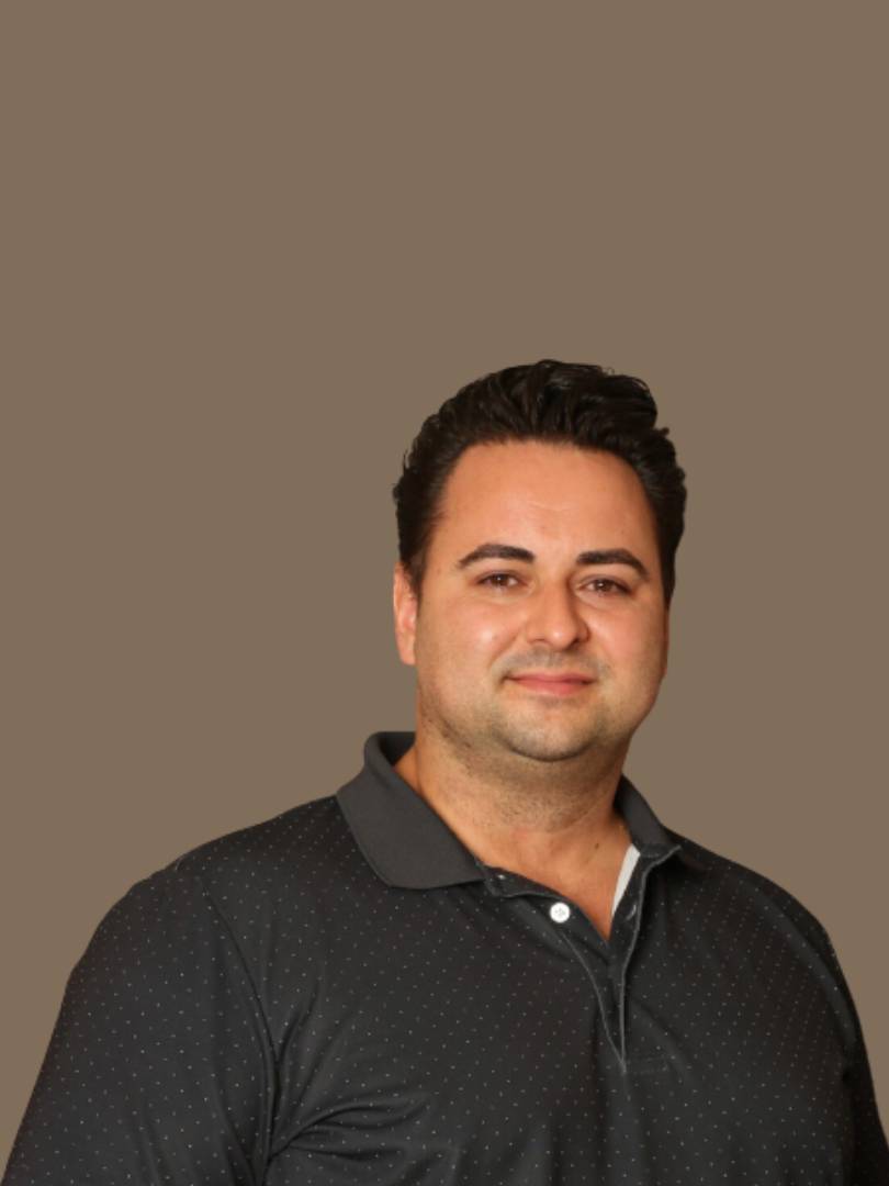 A man in black shirt standing next to brown wall.