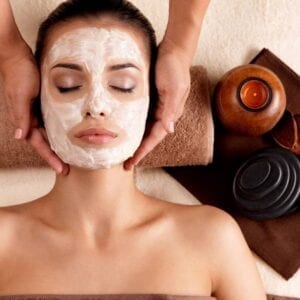 A woman getting her face washed with clay