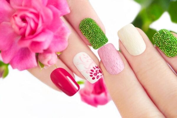 A woman is holding her nails with different designs on them.